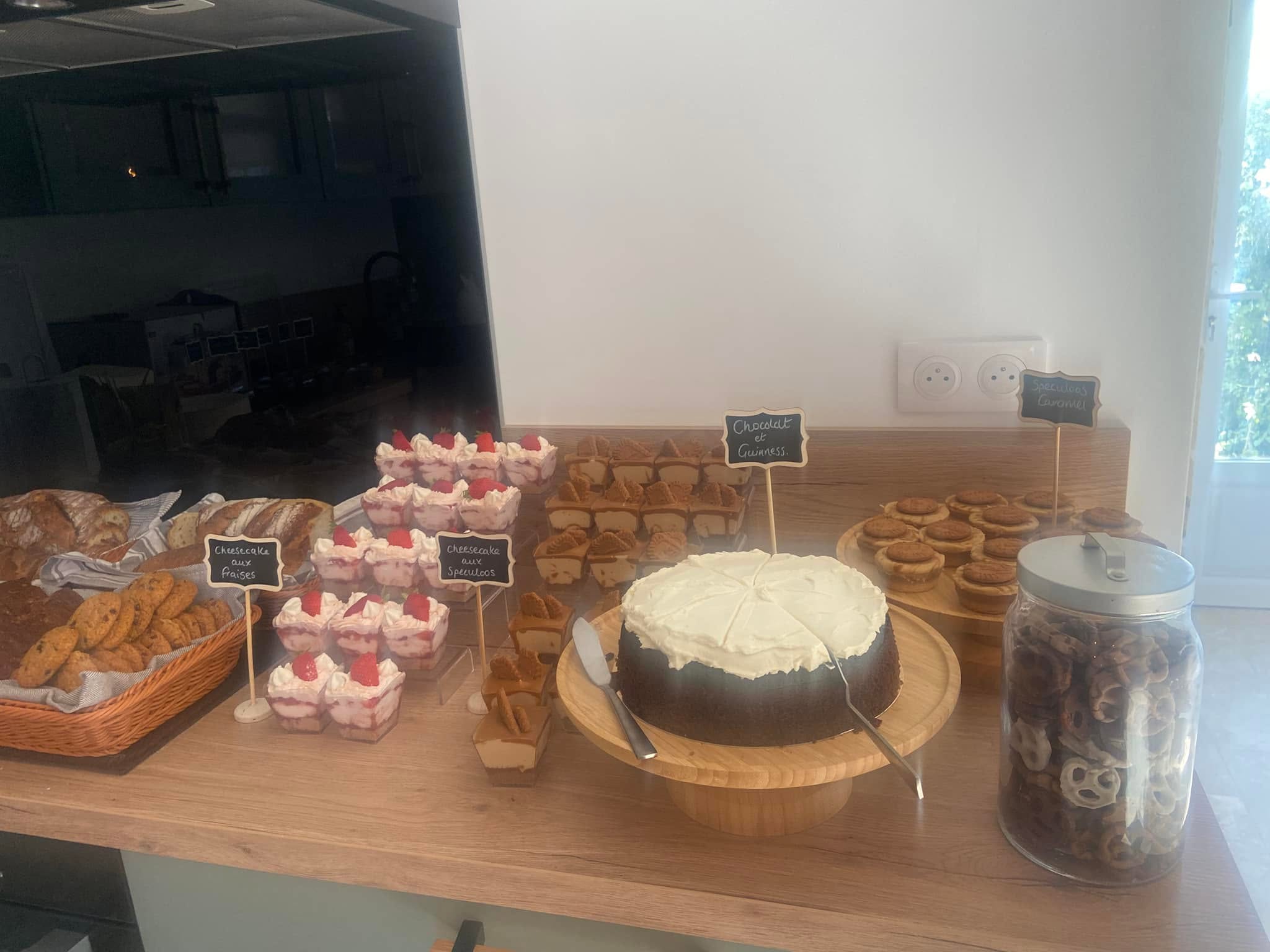 A bakery counter of strawberry cheesecake cups, speculoos cheesecakes, a chocolate and Guinness cake, cookies and fresh bread